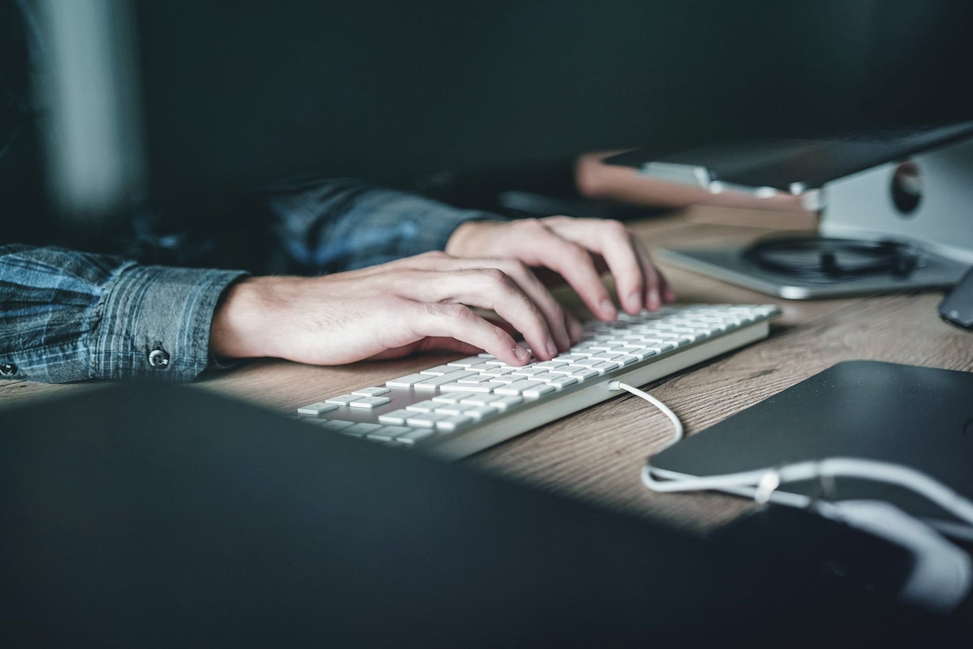 Mãos digitando em um teclado sobre uma mesa de escritório